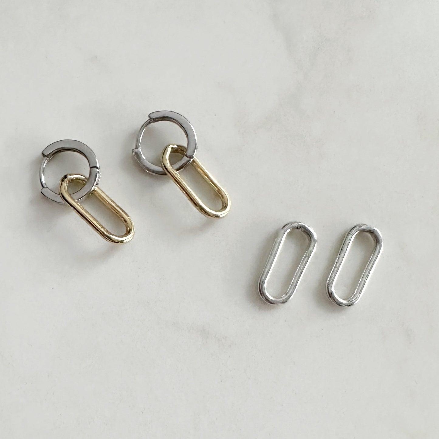 Pair of silver and gold hoop earrings on a light gray background