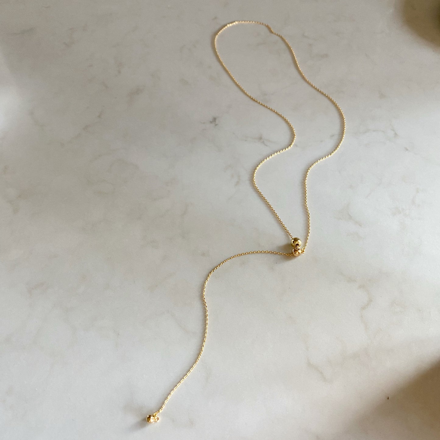 Adjustable lariat choker necklace on white marble background