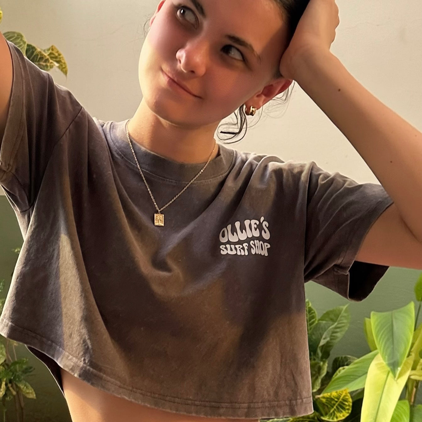 Person wearing a vacation pendant necklace with a surf shirt on