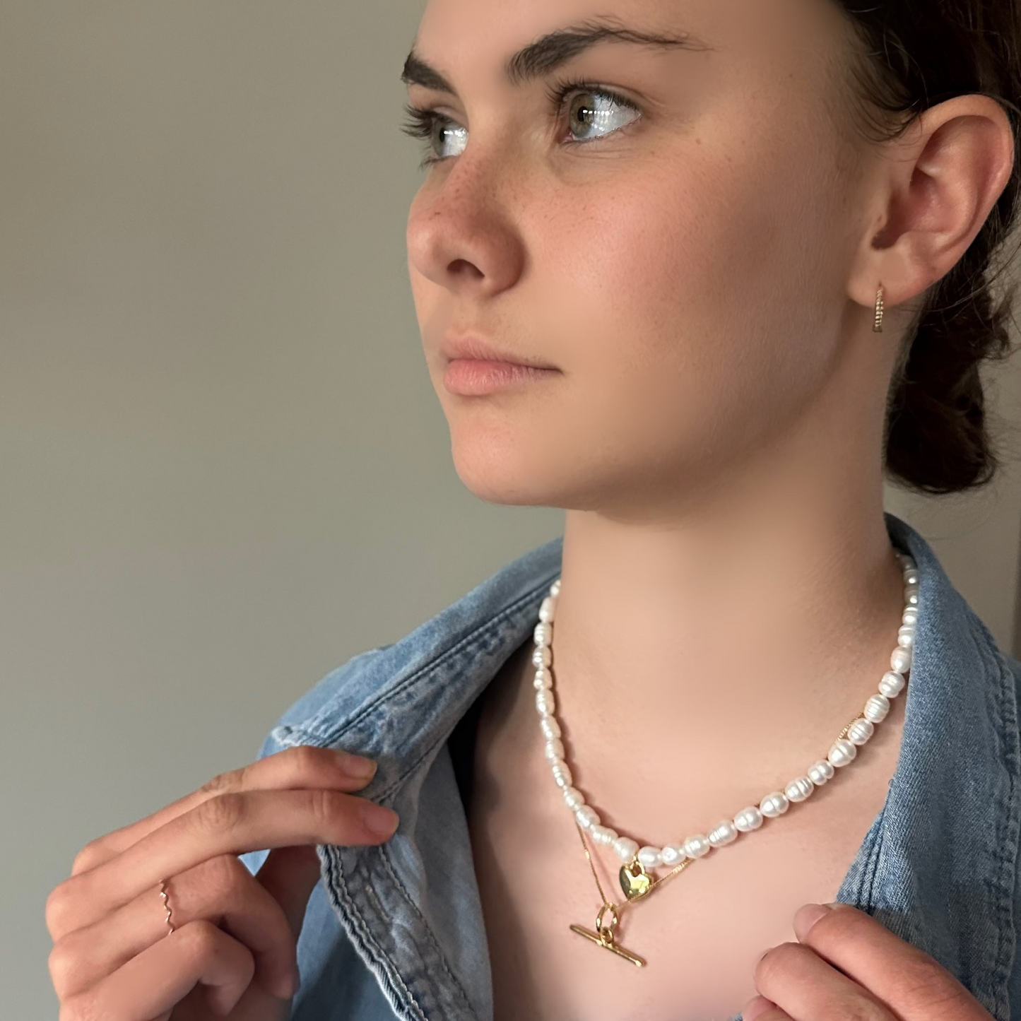 Woman wearing a pearl necklace and earrings, looking to the side.