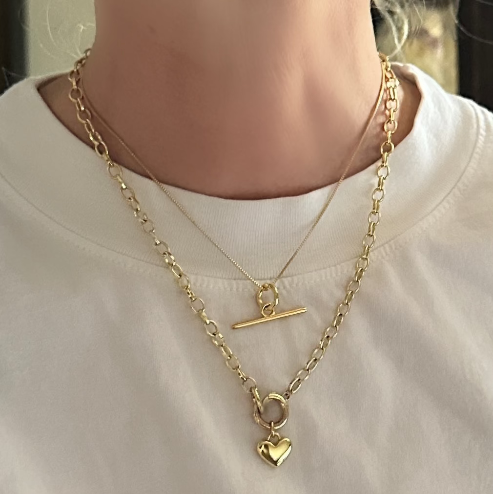 Gold necklace with a heart pendant on a white shirt