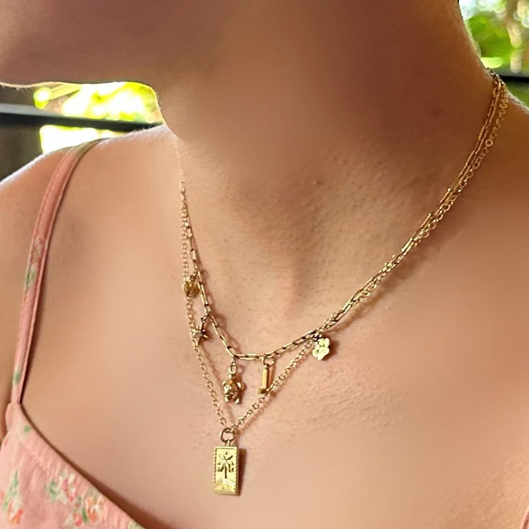 Close-up of a person wearing a gold necklace with a blurred background