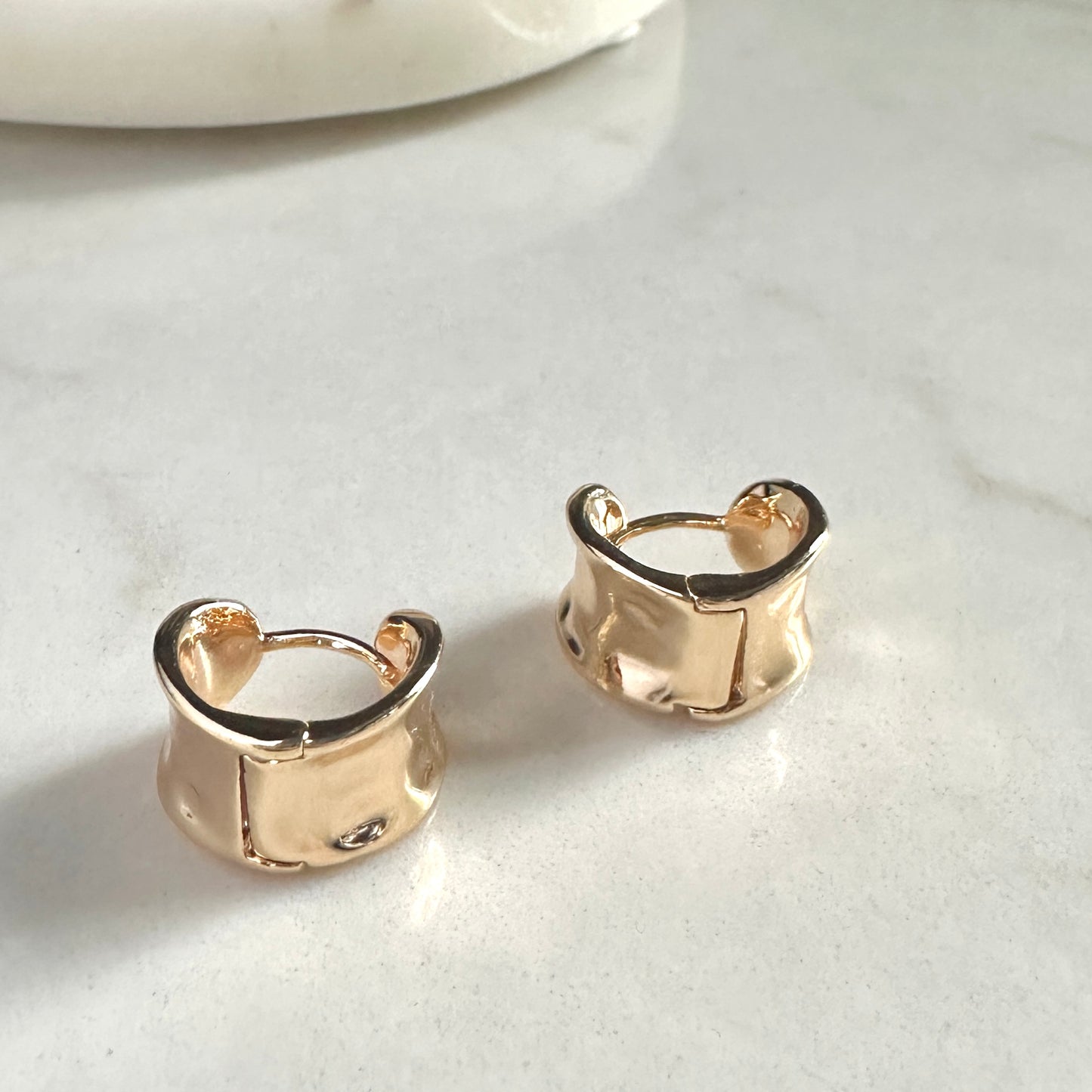 Gold hoop earrings on a light gray surface