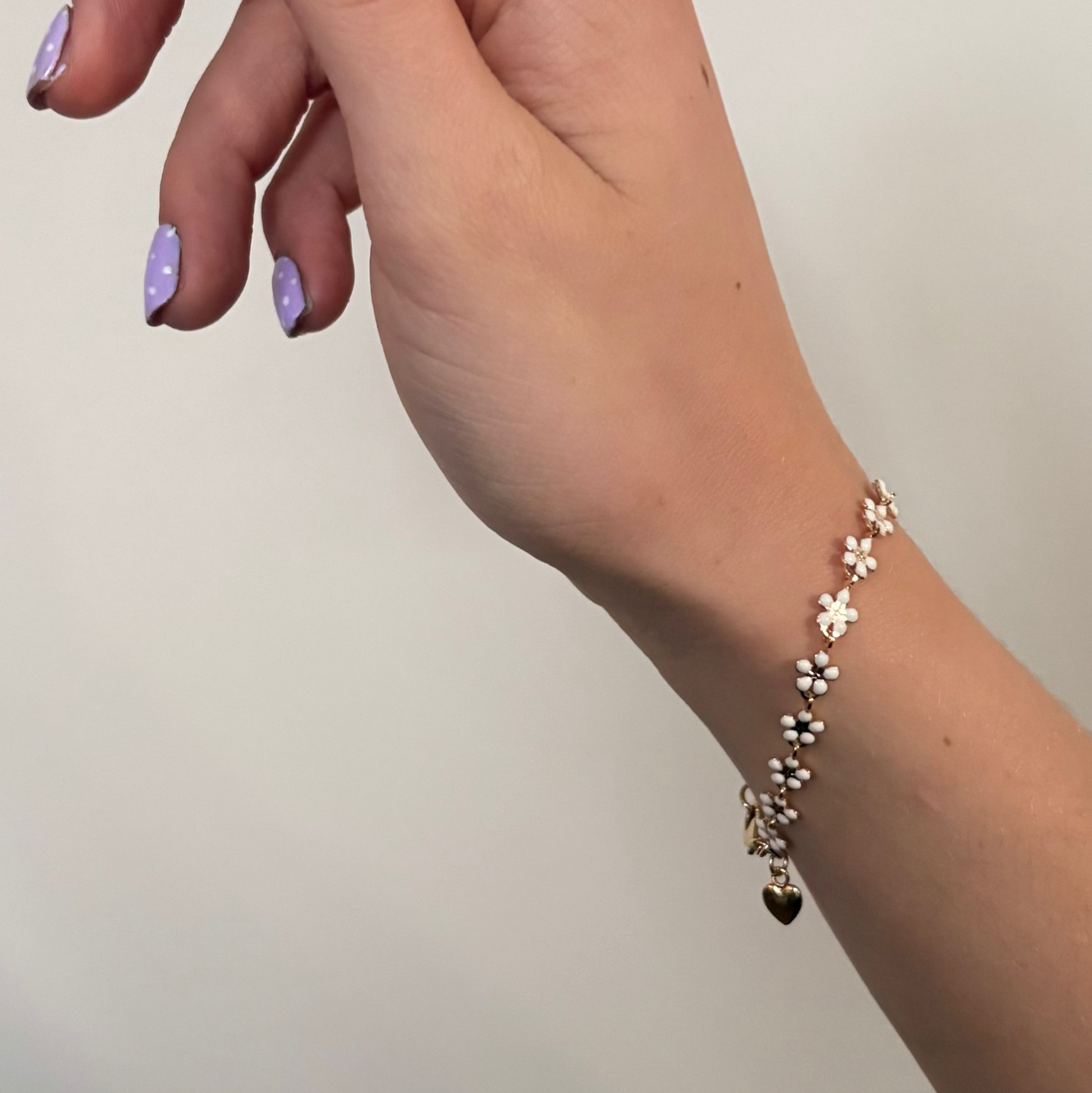 Hand wearing a floral bracelet on a plain background
