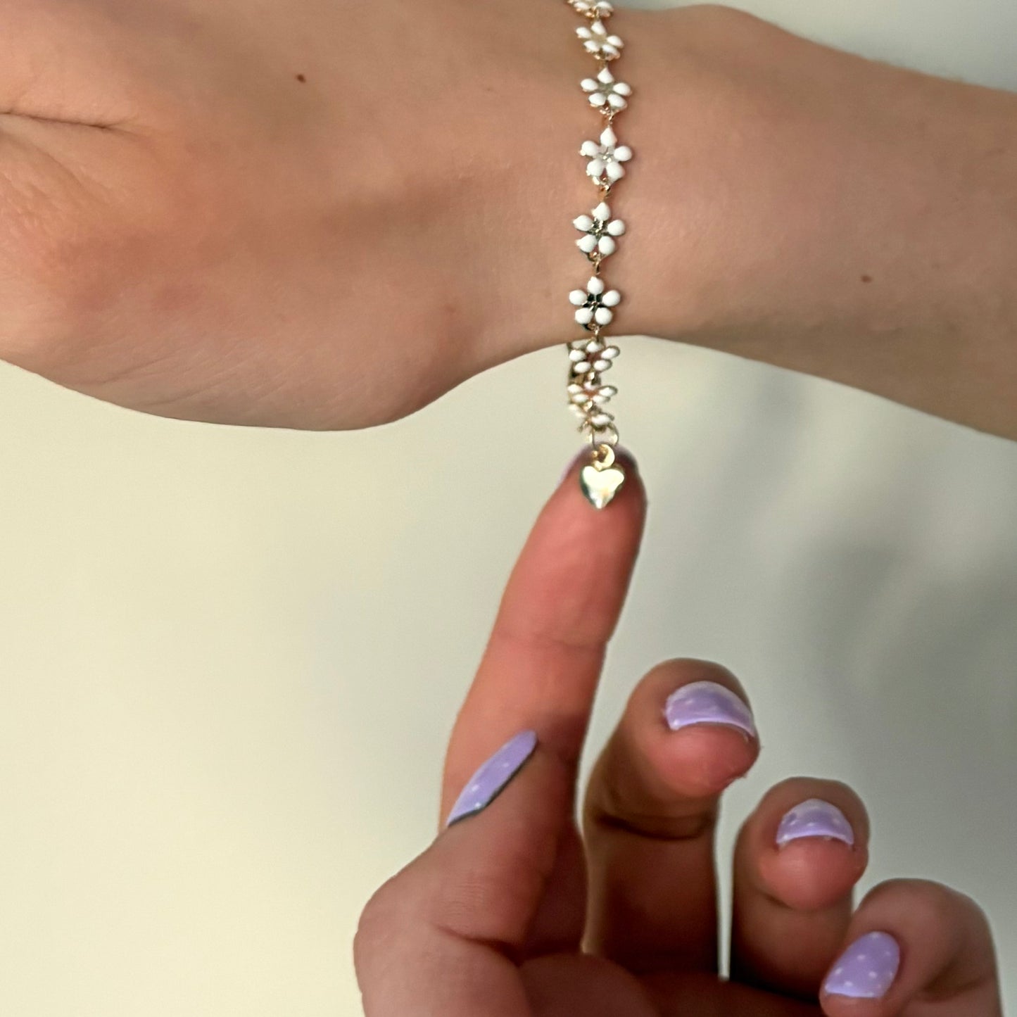 Bracelet with floral design on a wrist against a neutral background