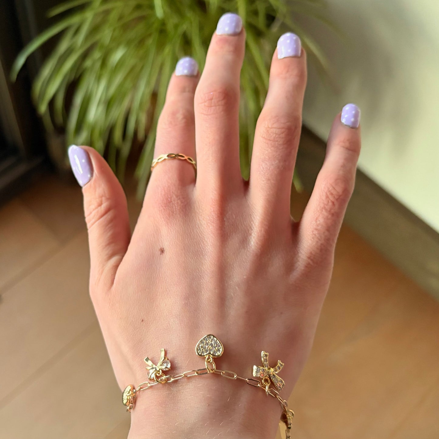 Hand with gold rings and bracelets against a blurred indoor background