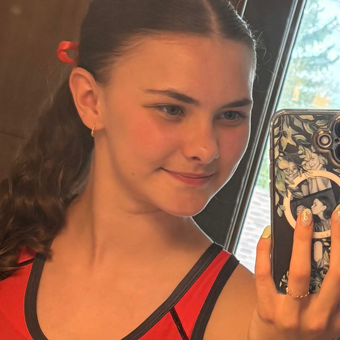 Woman taking a mirror selfie with a phone case featuring artistic design.