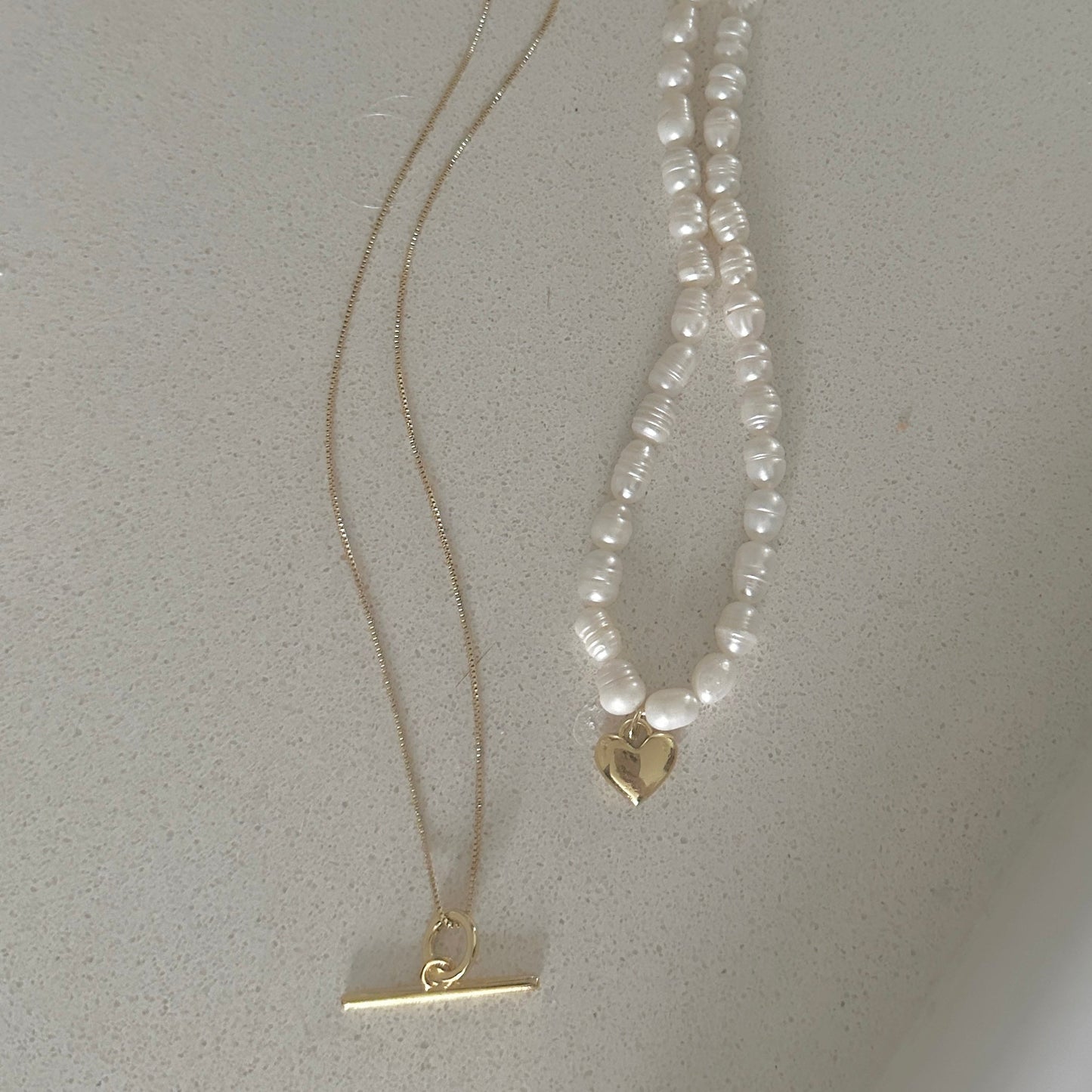 Pearl necklace with gold clasp on a light gray background