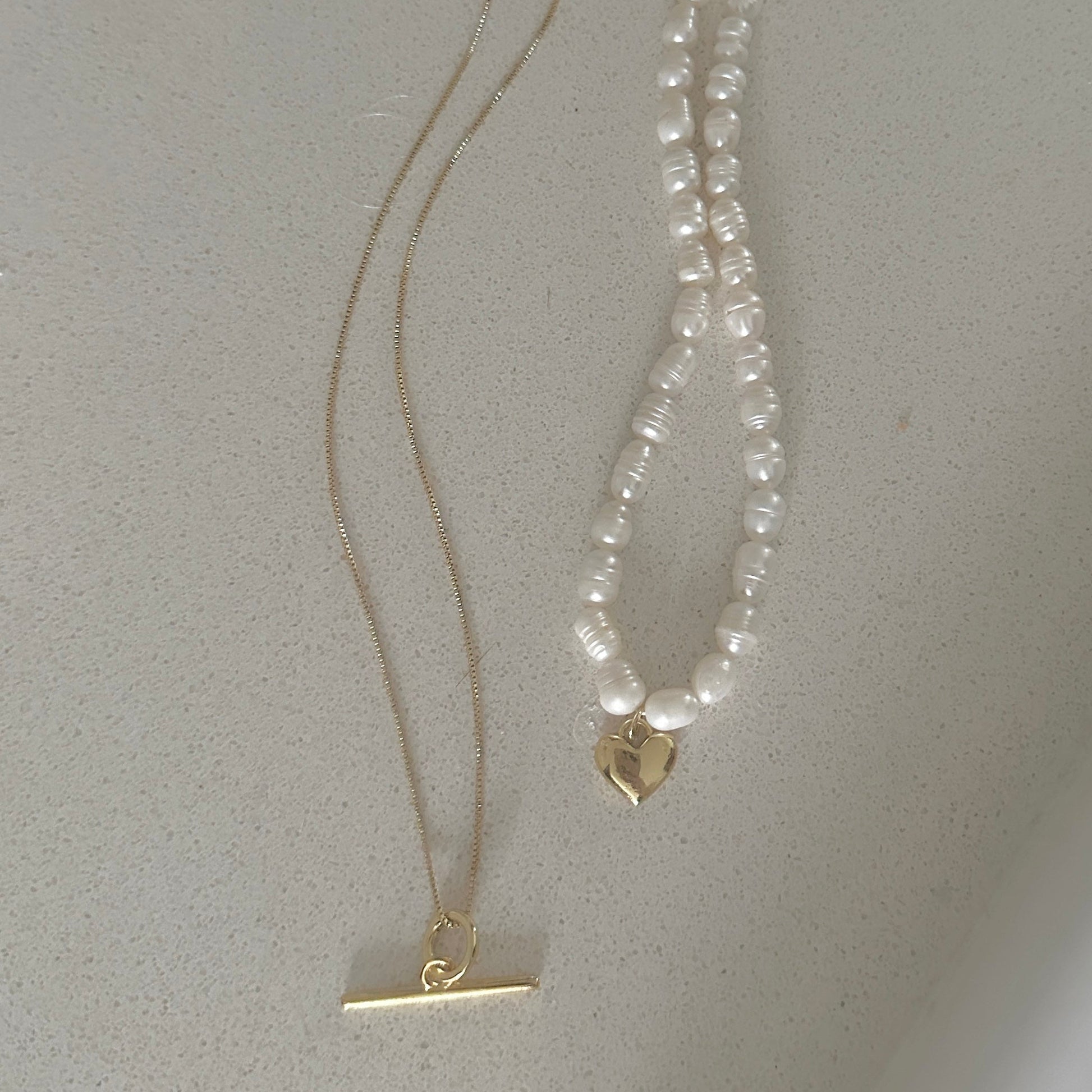 Pearl necklace with gold clasp on a light gray background