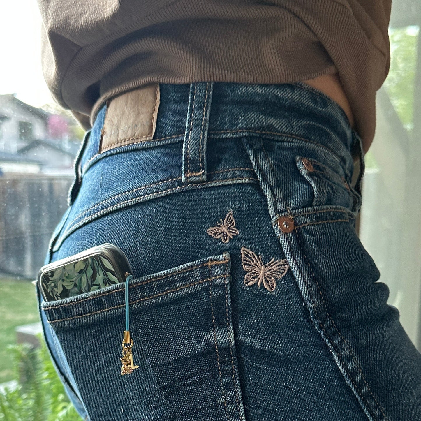 charm on cell phone in a back pocket