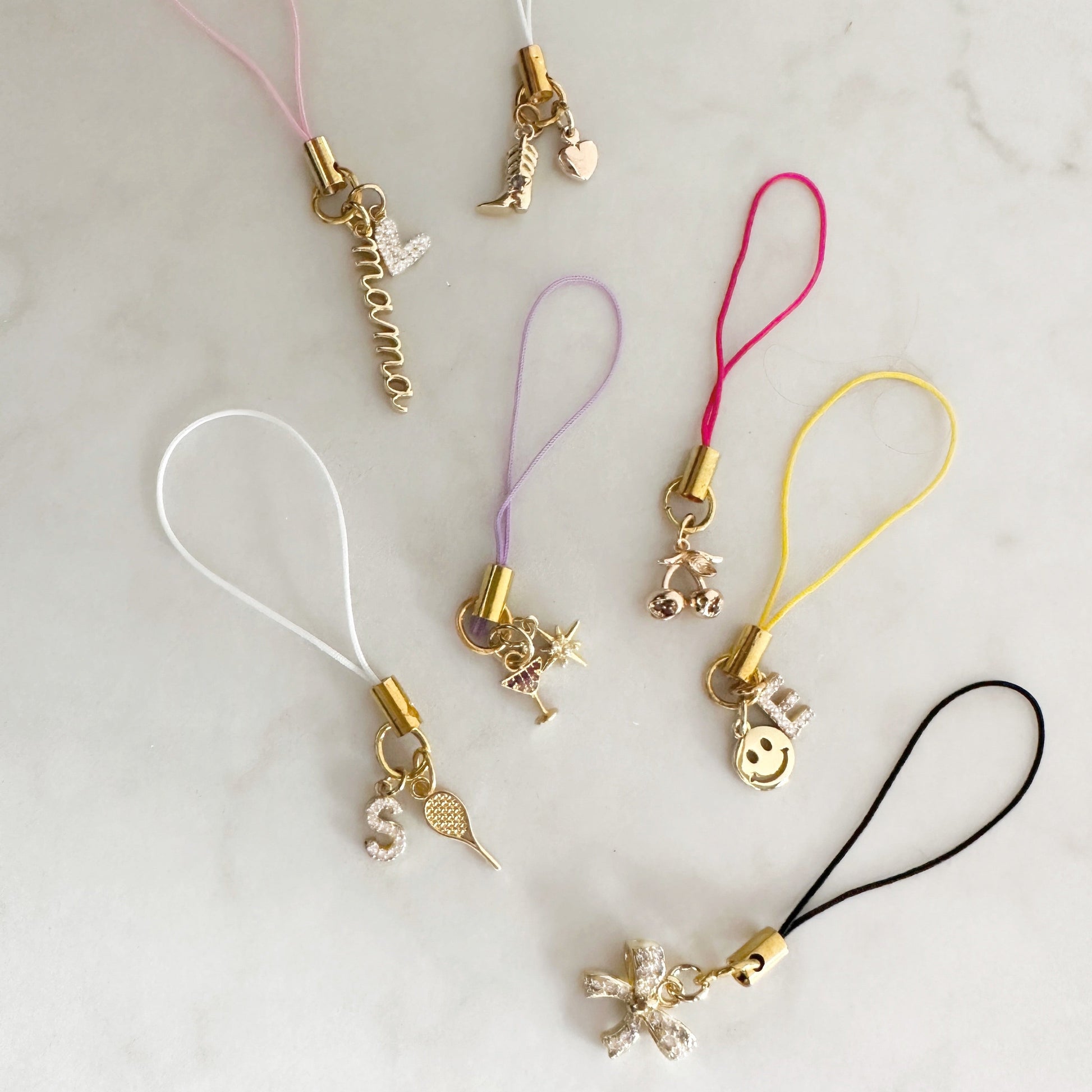 Set of five phone charms with various designs on a light gray background