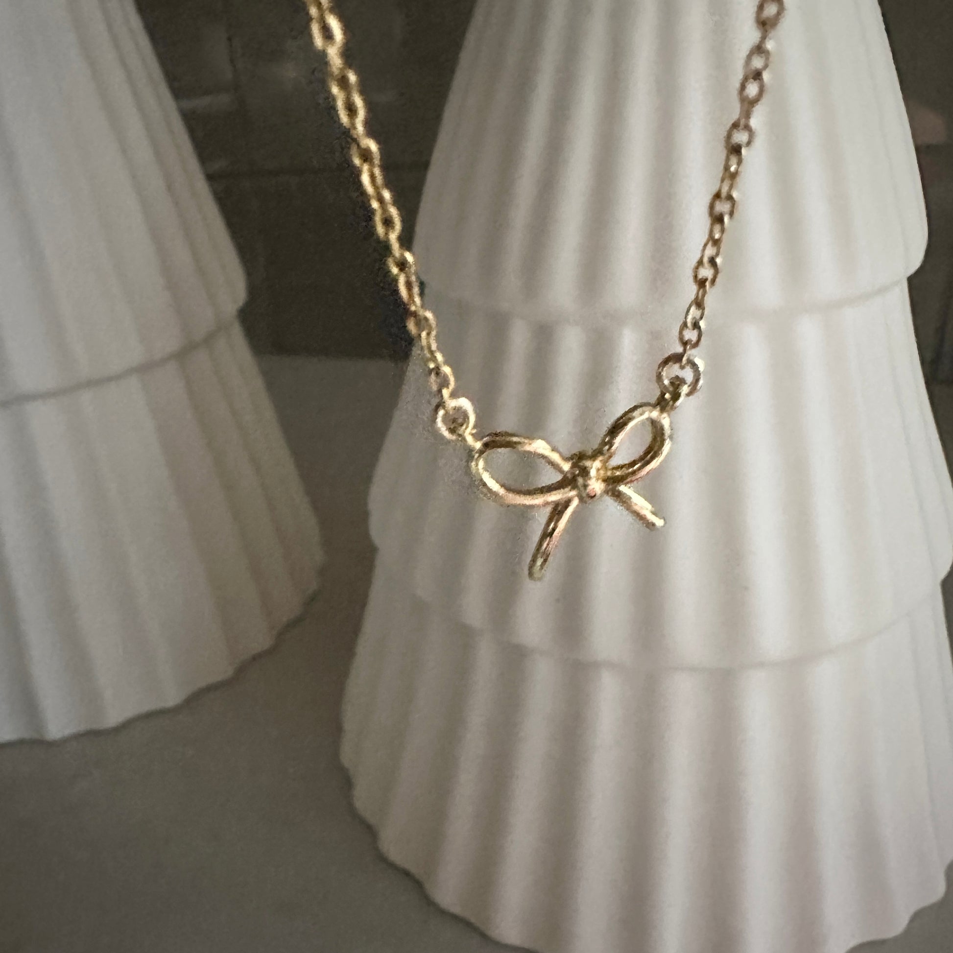 Gold bow-shaped necklace on a white dress form