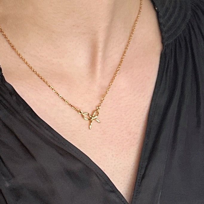 Gold necklace with a starfish pendant worn by a person in a black top.