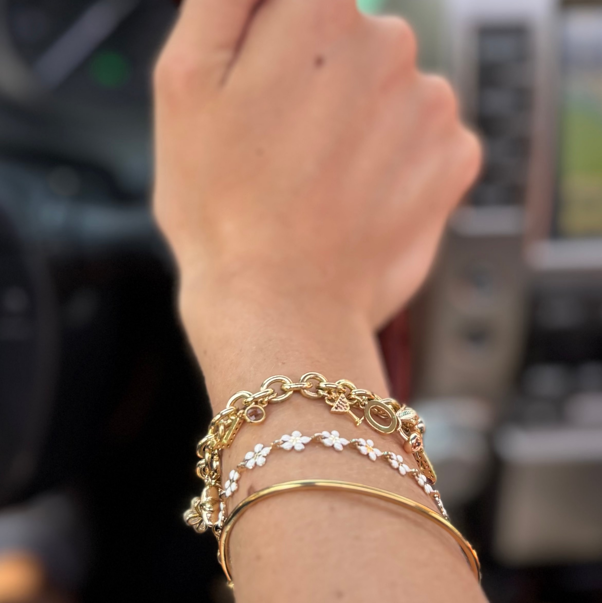 Close-up of a wrist wearing multiple gold bracelets with a blurred background