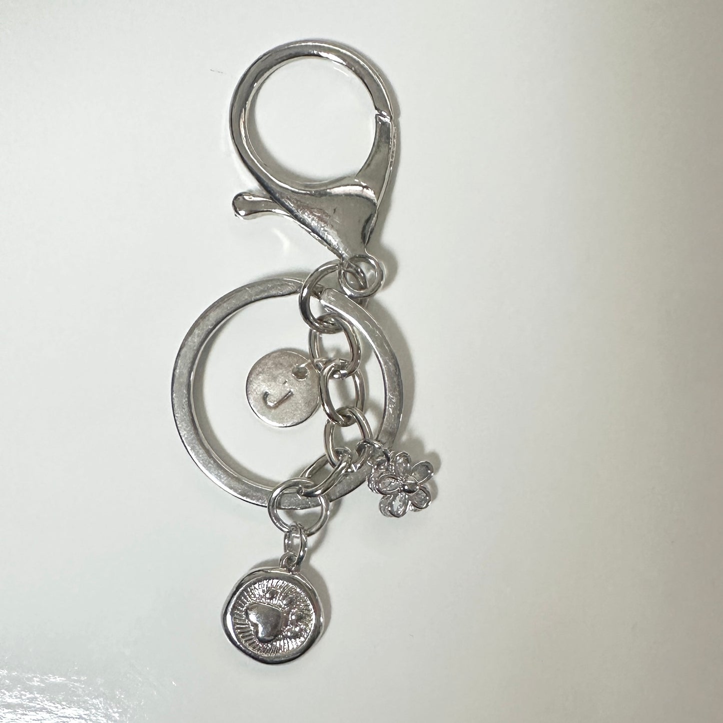 Silver keychain with circular design and charms on a white background