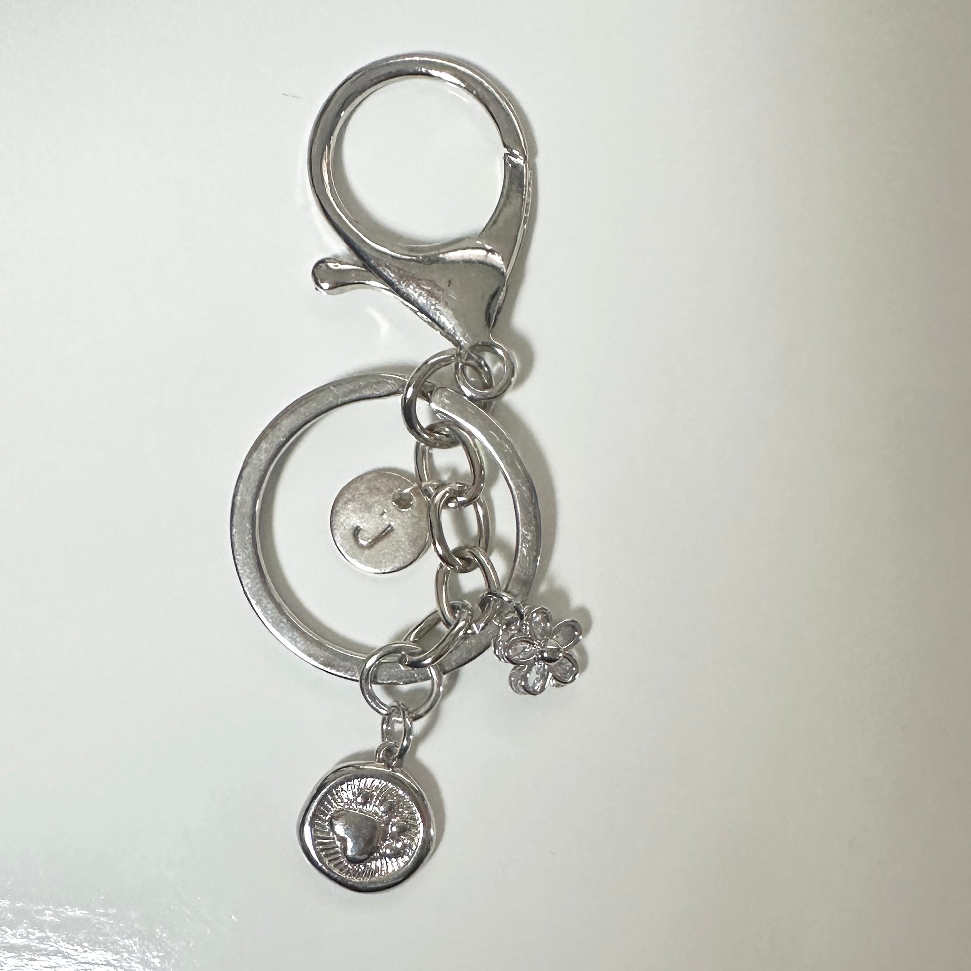 Silver keychain with circular design and charms on a white background