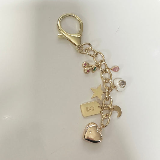 Gold keychain with various charms on a white background