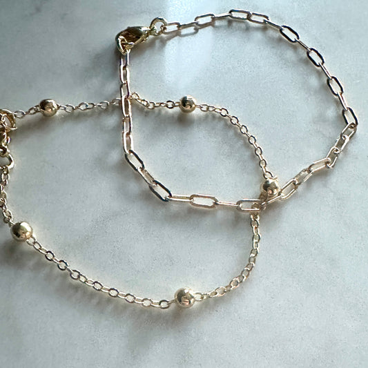 Silver chain bracelet with small beads on a light gray background