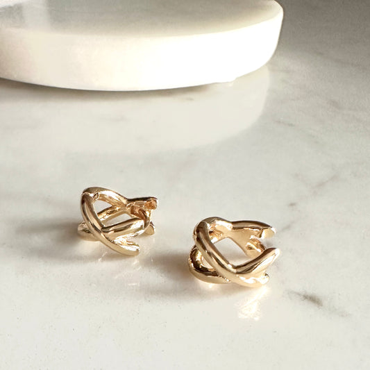Gold heart-shaped earrings on a marble surface
