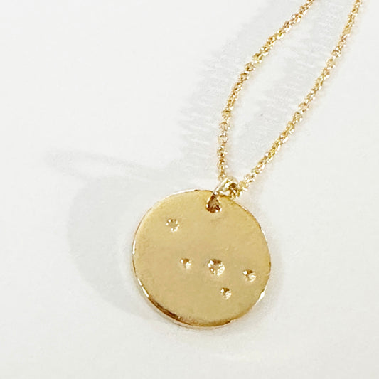 Gold necklace with a round pendant on a white background