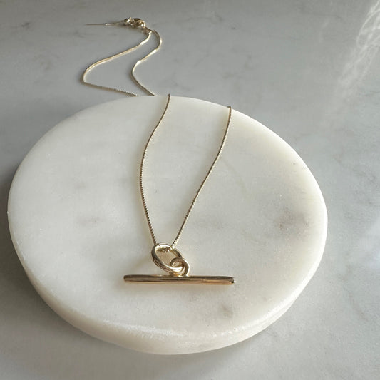 Gold necklace on a white circular stone surface