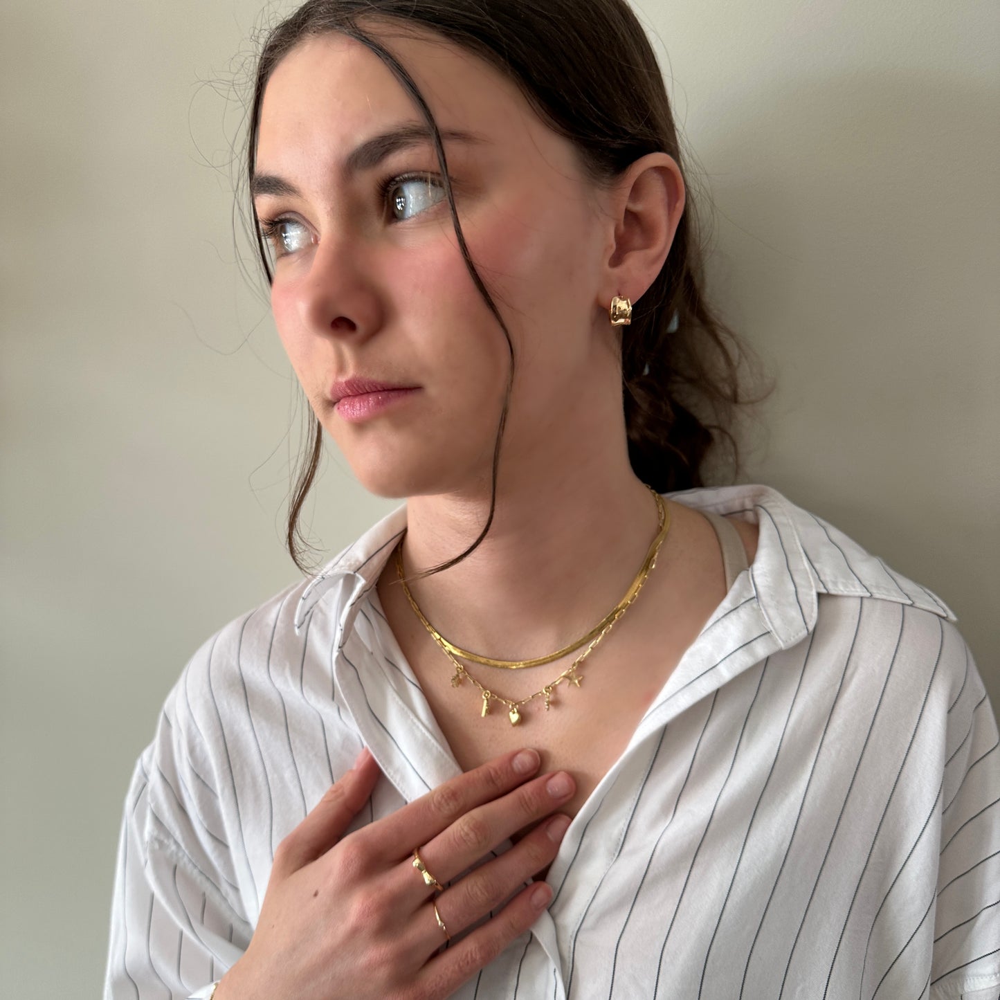 Woman wearing gold jewelry against a neutral background