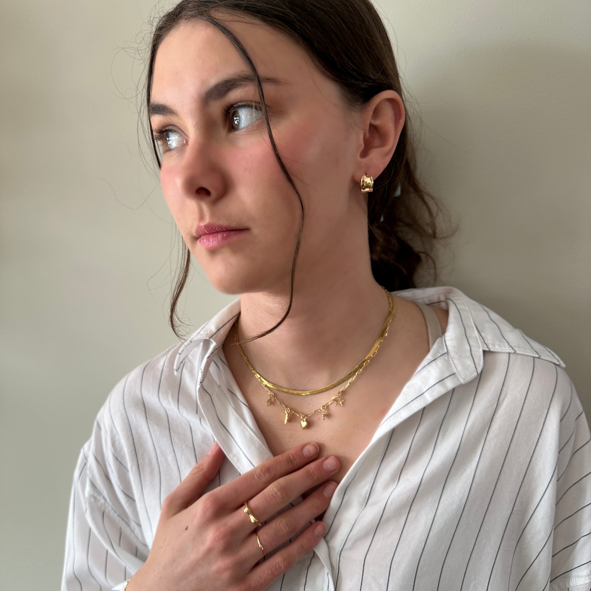 Woman wearing gold jewelry against a neutral background